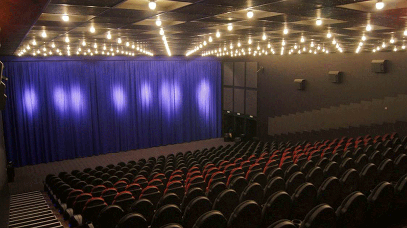 Stor tom biograf med mange biografsæder og et stort biograflærred med lilla lys